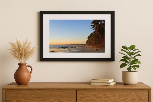 Framed beach print on a wall above a wooden console table with decorative items.
