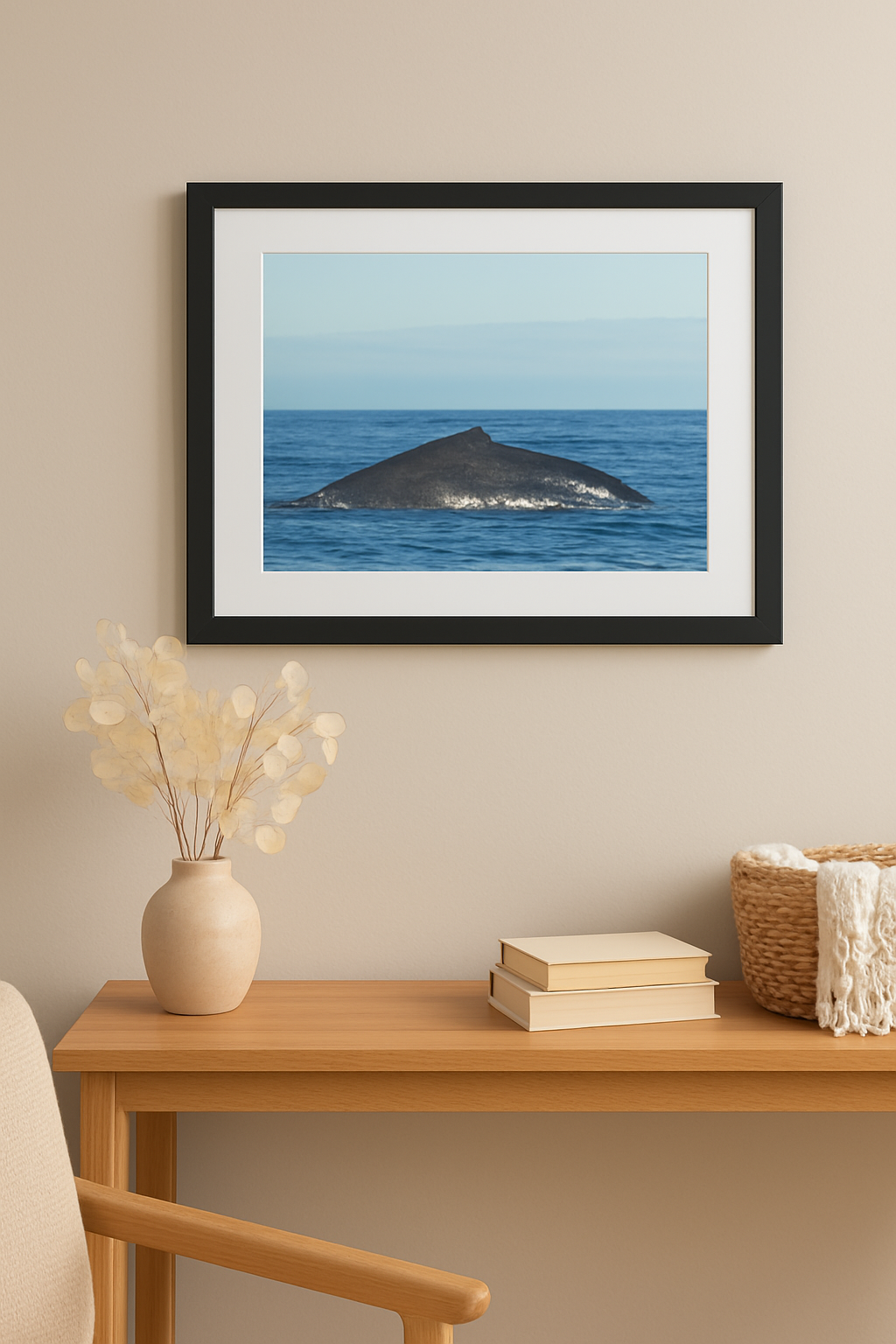 Framed picture of a whale in the ocean on a wall above a wooden table with decor items.