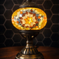Golden Star Turkish Mosaic Lamp lit at dusk, highlighting its antique-style metal base and shimmering mosaic.